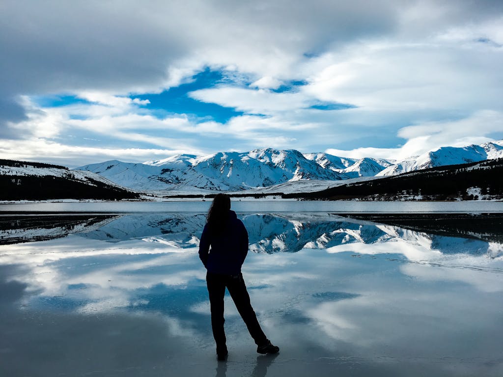 Silhouette Photo of Woman Facing Snow Capped Mountain