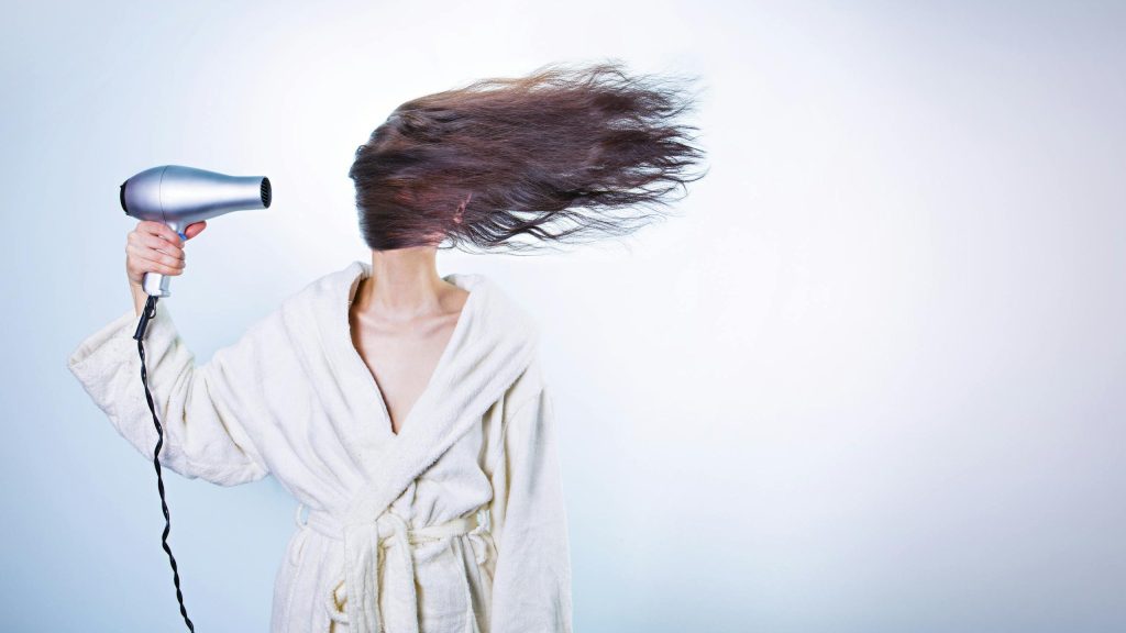 Woman Holding Gray Hair Dryer and Wearing White Bathrobe