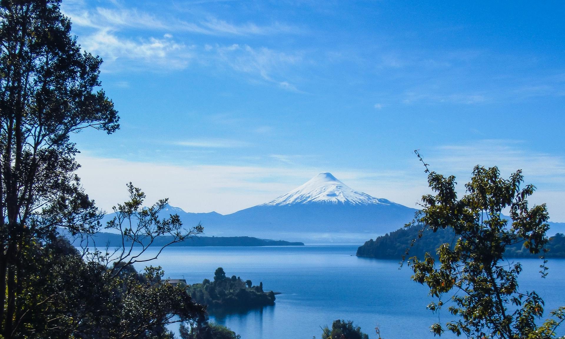 Breathtaking view of Osorno Volcano and Llanquihue Lake surrounded by lush trees in Frutillar, Chile.