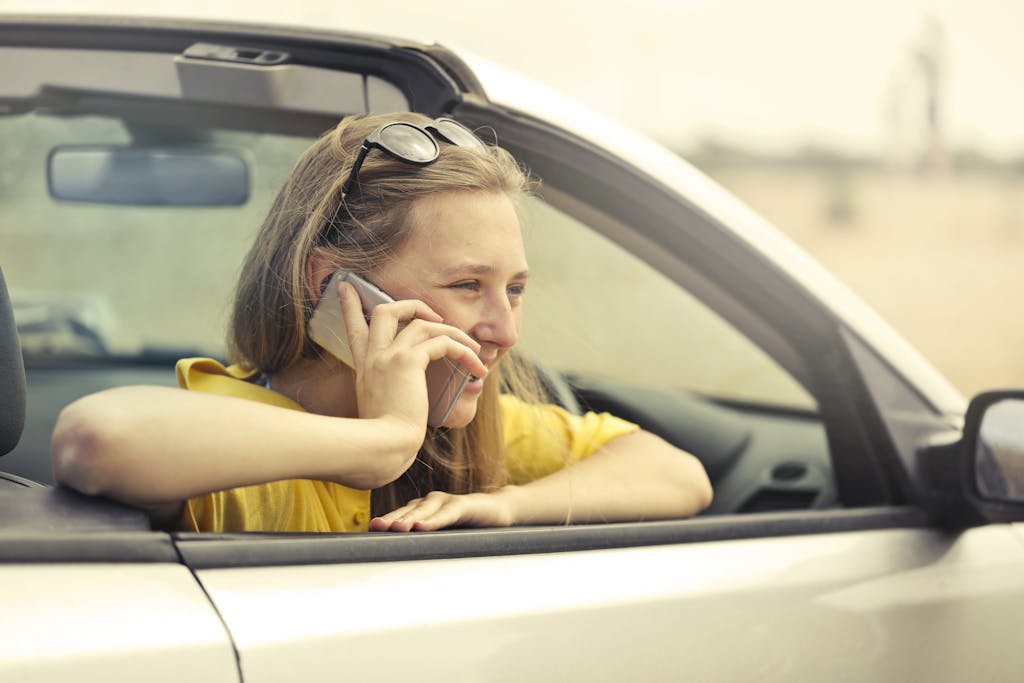 Woman smiling while talking on phone in a convertible car during a sunny day. She may be using an International roaming plan in Chile.