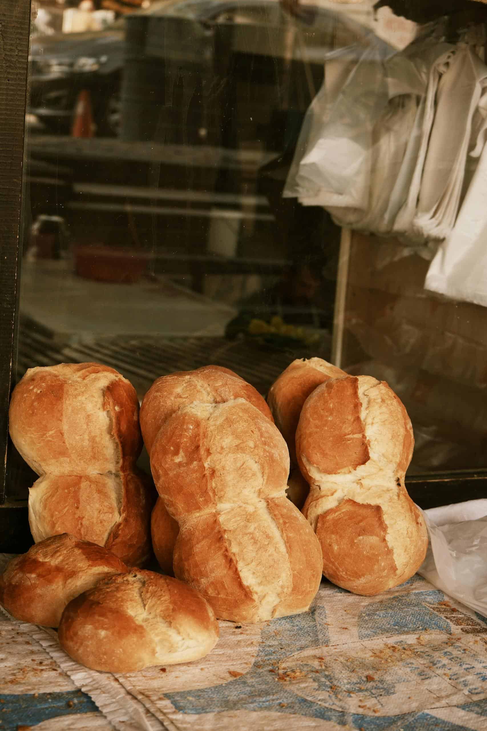 A rustic display of fresh artisan bread loaves in a bakery window setting.