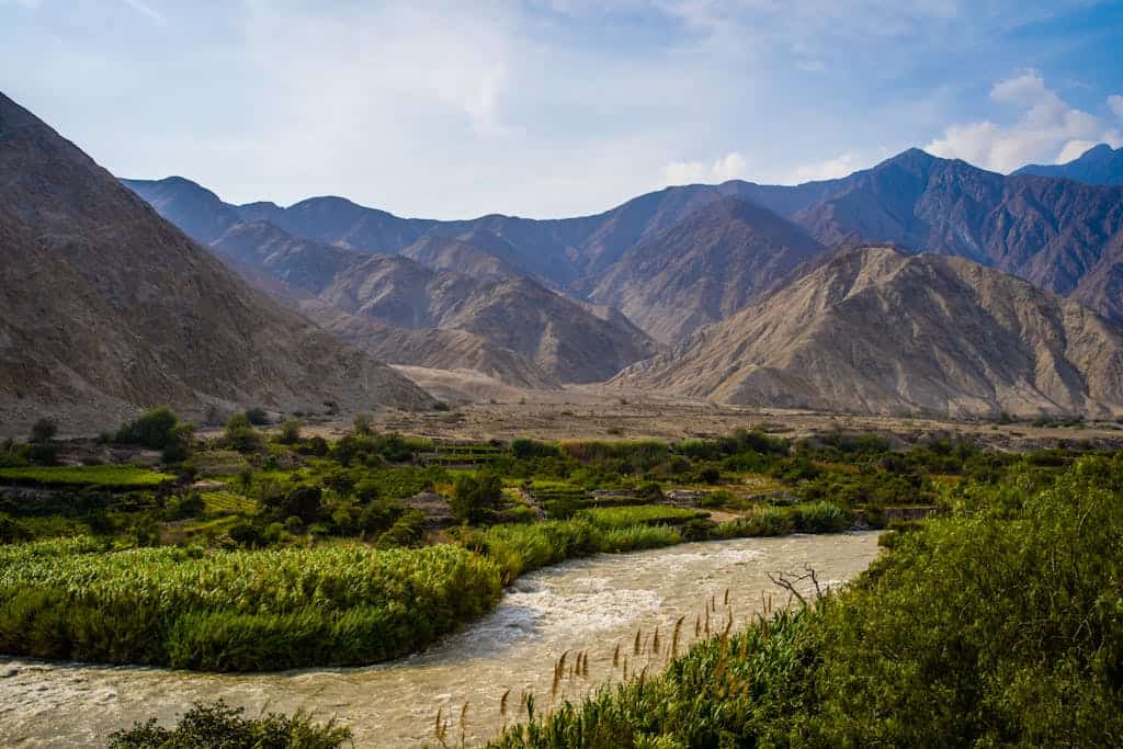 Breathtaking view of a river meandering through lush fields and mountains.