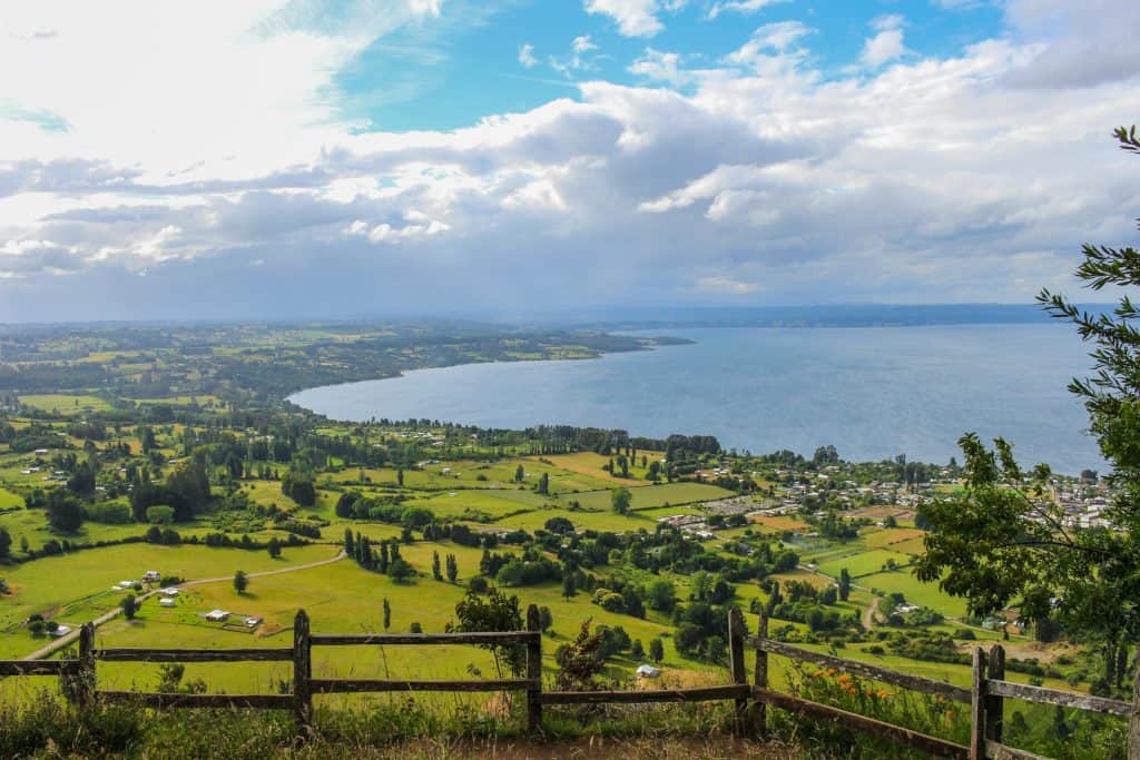 Breathtaking view of Lago Ranco, Chile, showcasing lush fields and the serene lake under a cloudy sky.